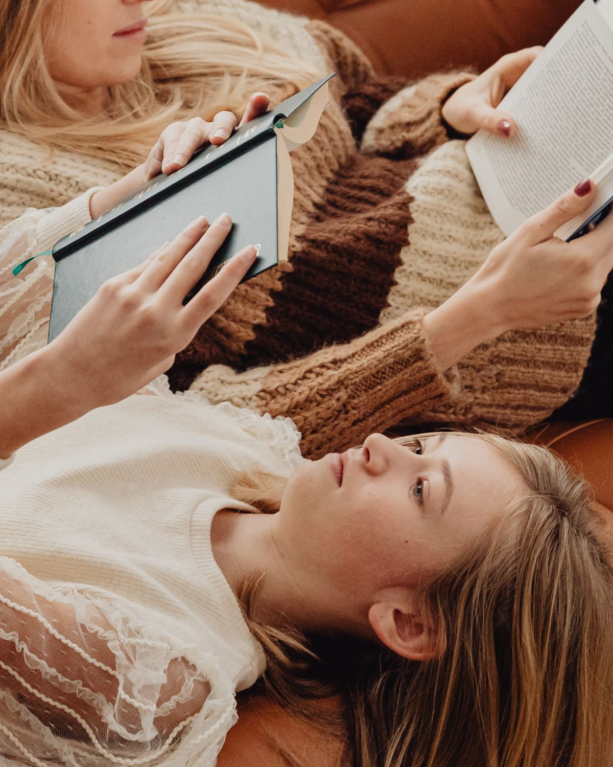 Two friends lying on a sofa, reading