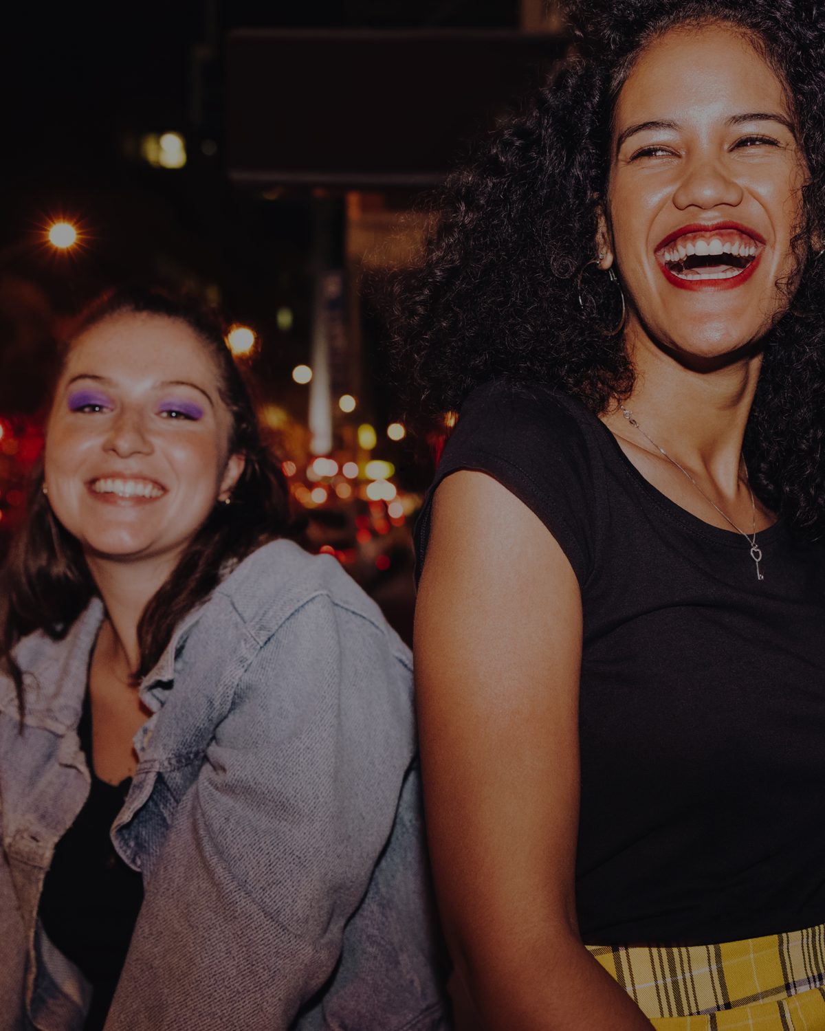 Two friends laughing on a city street at night