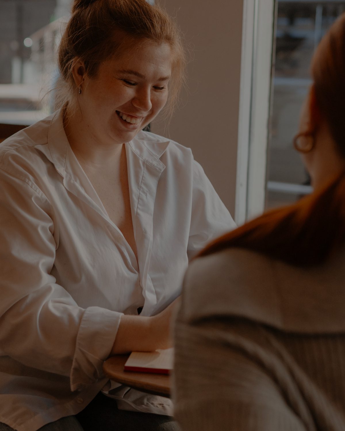 A woman laughing across a café table